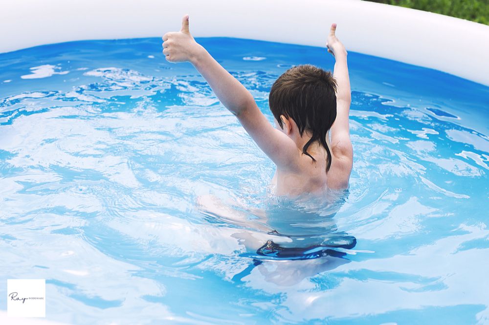 ビニールプールでガッツポーズをする子どもの後ろ姿のイメージ