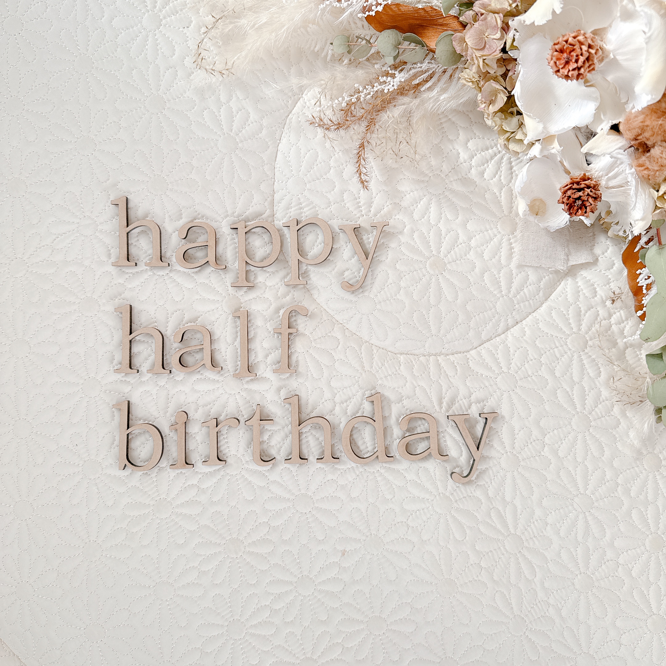happy half birthdayの木製レターバナーと白いお花の飾り付け