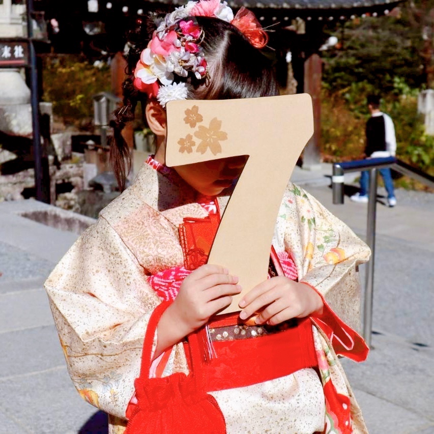七五三のビッグナンバーバナーと千歳飴プレートを持った着物の女の子