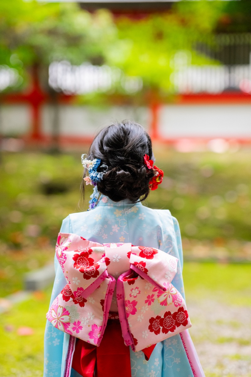 七五三の着物を着た女の子が神社の石段に座っている写真