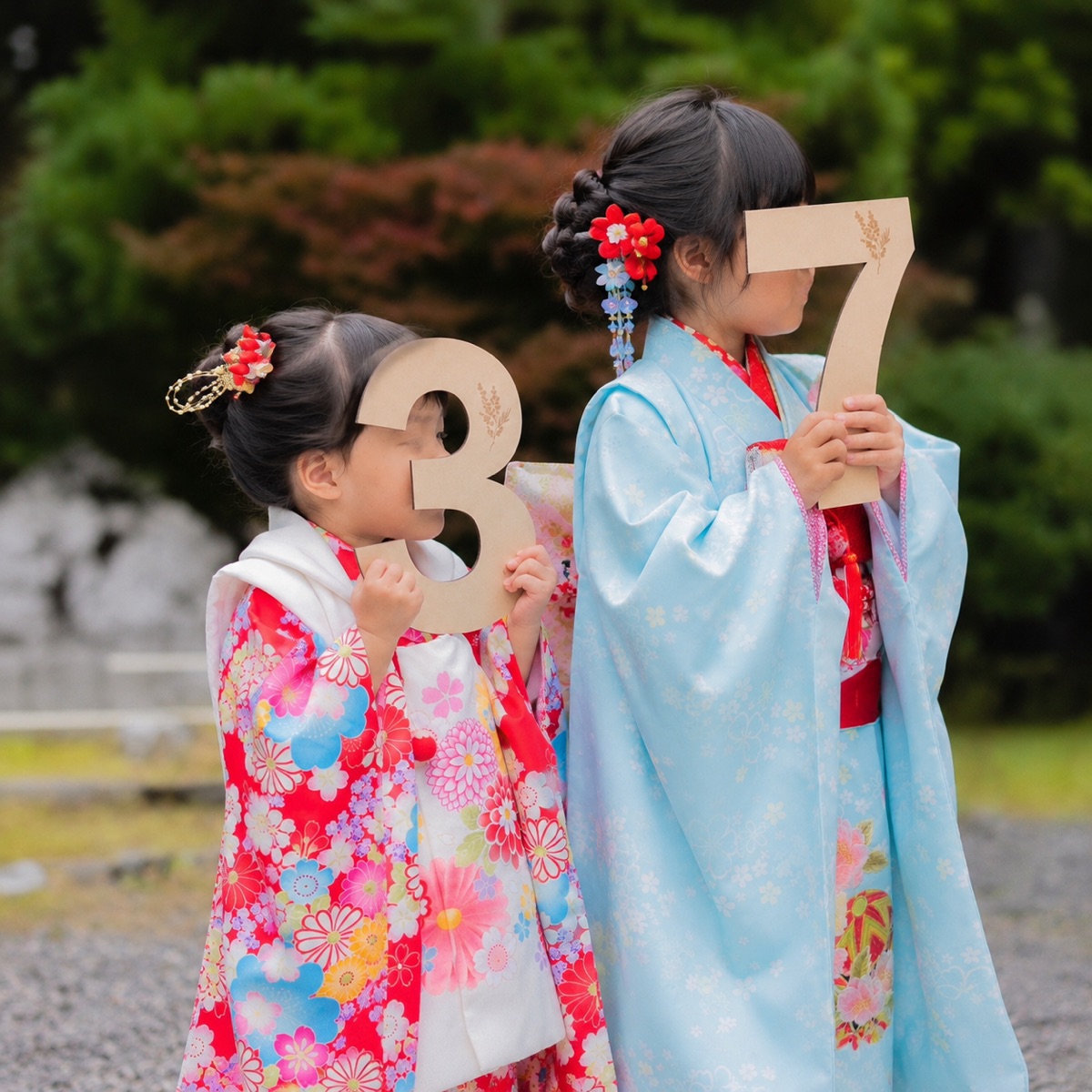 3と7の木製ナンバーを持つ着物姿の七五三の姉妹。神社での当日撮り